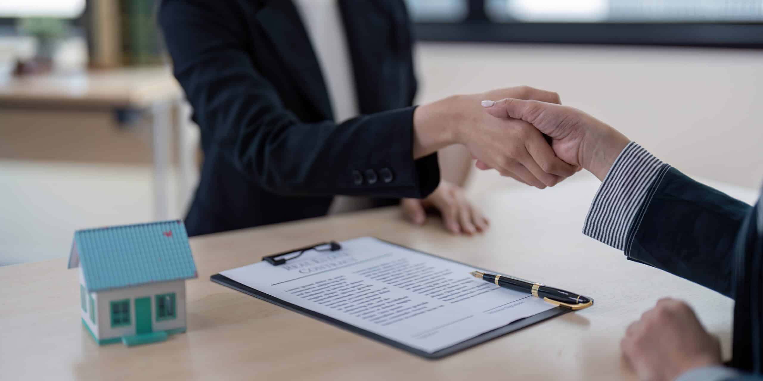 Two lawyers shaking hands after coming to an agreement during contract negotiations on behalf of their clients.