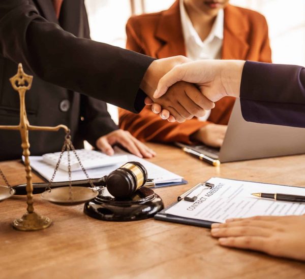 Two people shaking hands over a desk with a commercial real estate contract agreement in Nassau County on the table.